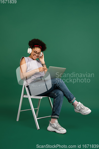 Image of African-american woman\'s portrait isolated on green studio background with copyspace