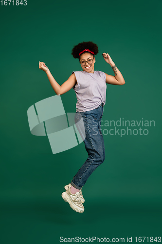 Image of African-american woman\'s portrait isolated on green studio background with copyspace