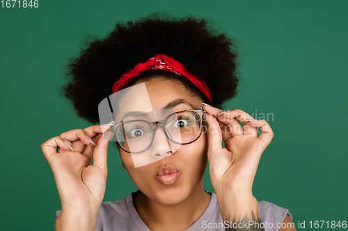 Image of African-american woman\'s portrait isolated on green studio background with copyspace