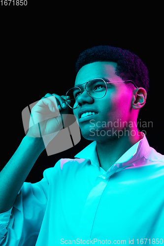 Image of African-american man\'s portrait isolated on black studio background in multicolored neon light