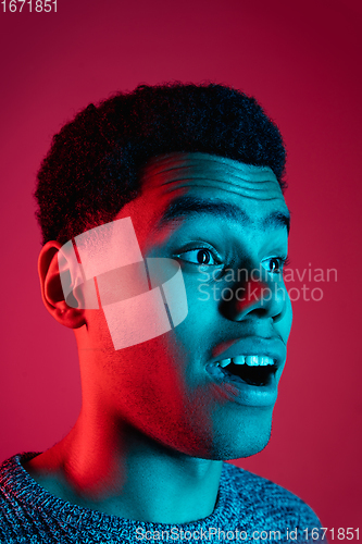 Image of African-american man\'s portrait isolated on red studio background in multicolored neon light