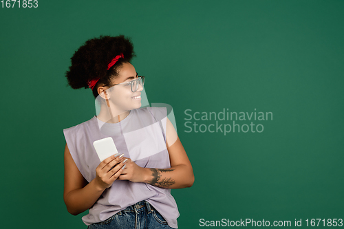 Image of African-american woman\'s portrait isolated on green studio background with copyspace