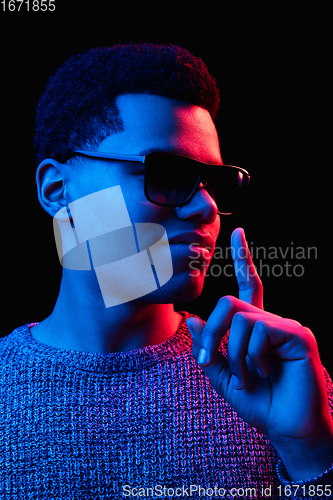 Image of African-american man\'s portrait isolated on black studio background in multicolored neon light