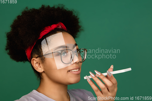 Image of African-american woman\'s portrait isolated on green studio background with copyspace