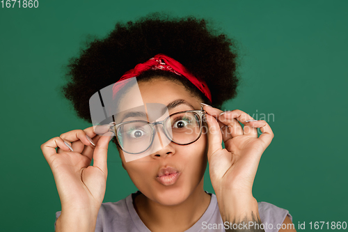 Image of African-american woman\'s portrait isolated on green studio background with copyspace