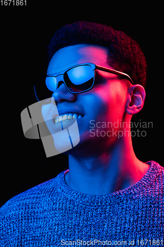 Image of African-american man\'s portrait isolated on black studio background in multicolored neon light