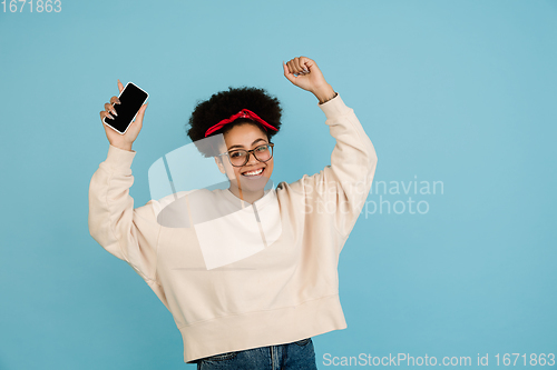 Image of African-american woman\'s portrait isolated on blue studio background with copyspace