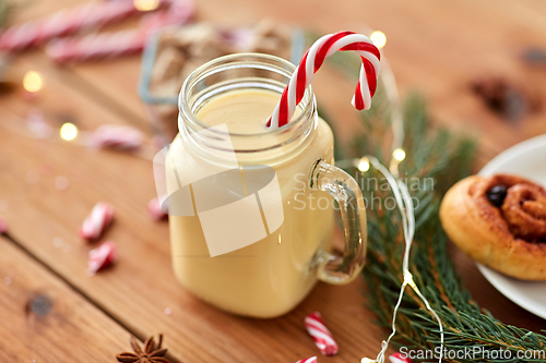 Image of eggnog with candy cane in mug and cinnamon buns