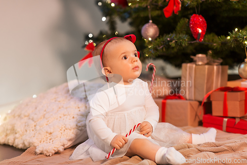 Image of baby girl at christmas tree with gifts at home