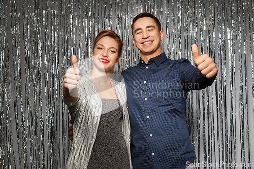 Image of couple in party clothes showing thumbs up