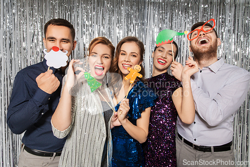 Image of happy friends posing with christmas party props