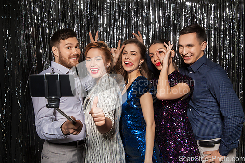 Image of happy friends taking selfie by smartphone at party