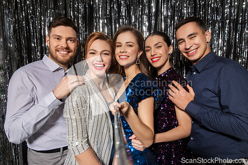 Image of happy friends taking selfie at party