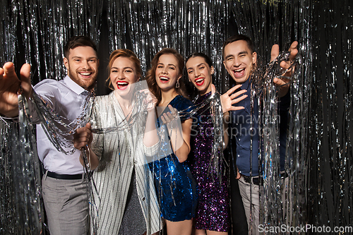 Image of happy friends in party clothes with tinsel curtain