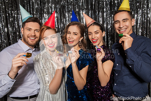 Image of happy couple with party blowers having fun