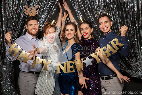 Image of happy friends posing with new year banner
