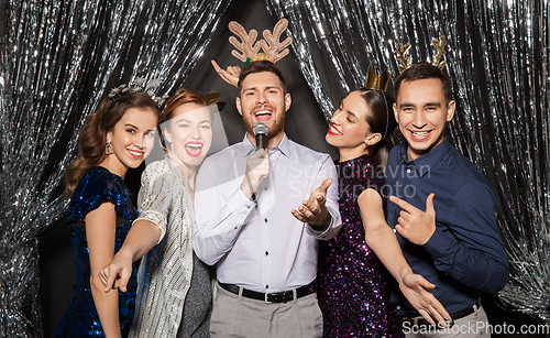 Image of friends with microphone singing at christmas party