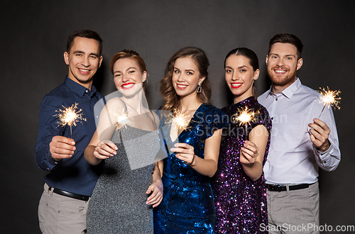 Image of happy friends in party clothes with sparklers