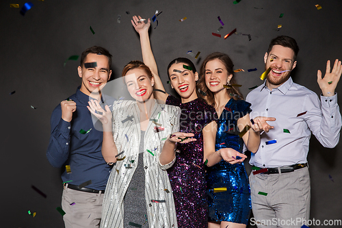 Image of happy friends at party under confetti over black