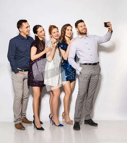 Image of happy friends taking selfie by smartphone at party