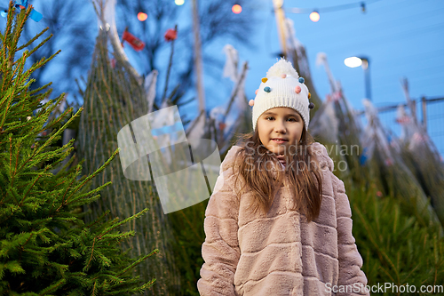 Image of little girl choosing christmas tree at market