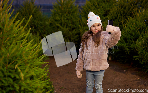 Image of little girl taking selfie at christmas tree market