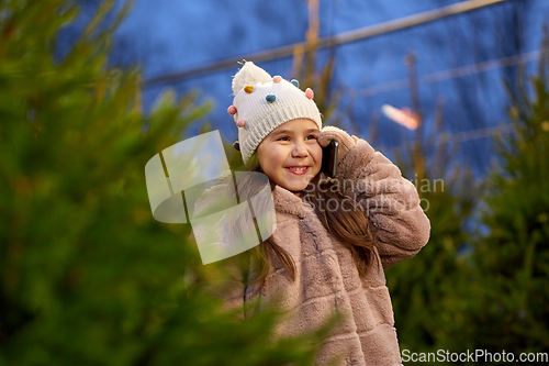 Image of girl calling on smartphone over christmas trees