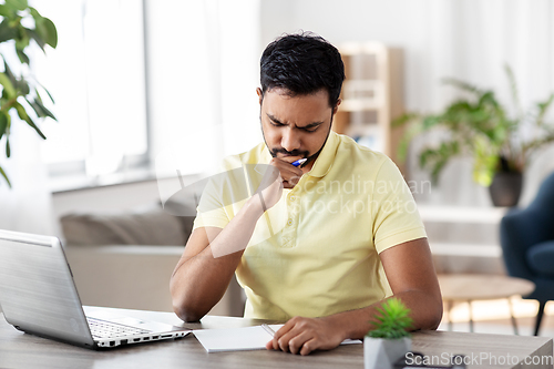 Image of indian man with notebook and laptop at home office