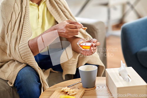 Image of sick man preparing hot tea with honey at home