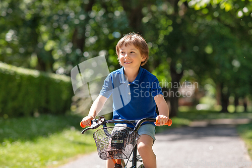 Image of happy little boy riding bicycle at summer park