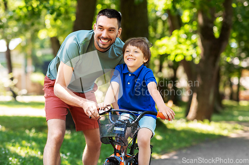 Image of father teaching little son to ride bicycle at park