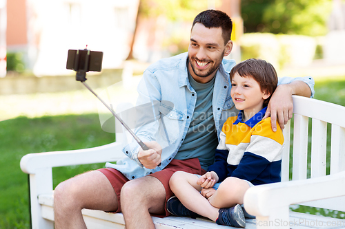 Image of father and son taking selfie with phone at park