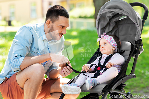 Image of happy father with child in stroller at summer park