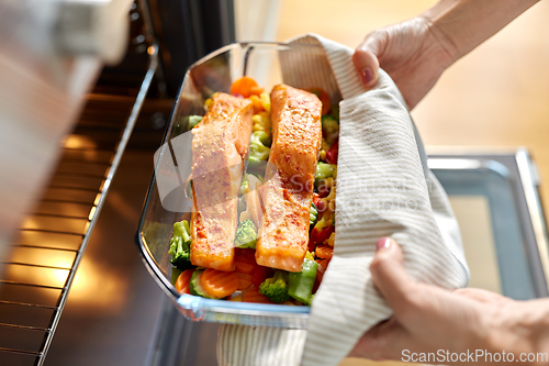 Image of woman cooking food in oven at home kitchen