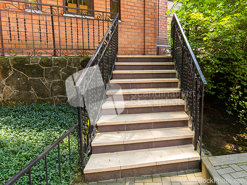 Image of A beautiful staircase with metal railings rises to a red brick building