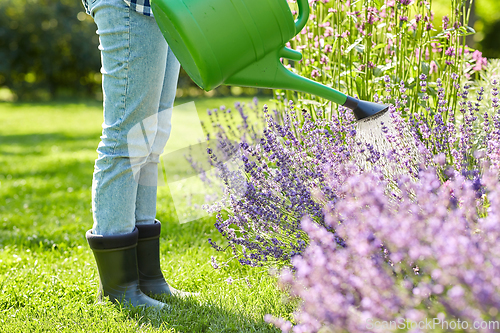 Image of young woman watering flowers at garden