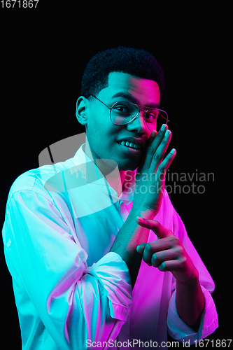 Image of African-american man\'s portrait isolated on black studio background in multicolored neon light