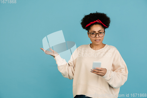 Image of African-american woman\'s portrait isolated on blue studio background with copyspace