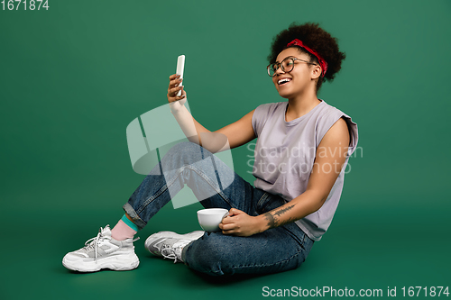 Image of African-american woman\'s portrait isolated on green studio background with copyspace