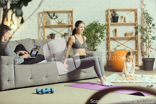 Image of Young woman exercising fitness, aerobic, yoga at home, sporty lifestyle. Getting active during lockdown, quarantine. Home gym.