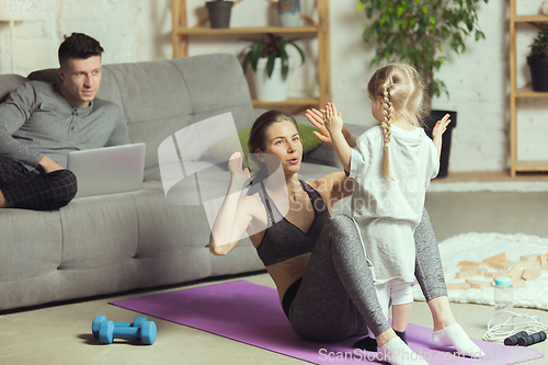 Image of Young woman exercising fitness, aerobic, yoga at home, sporty lifestyle. Getting active during lockdown, quarantine. Home gym.