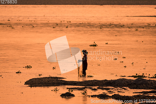 Image of Asian Woman fishing in the river, silhouette at sunset