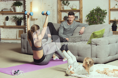 Image of Young woman exercising fitness, aerobic, yoga at home, sporty lifestyle. Getting active during lockdown, quarantine. Home gym.