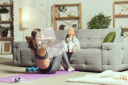 Image of Young woman exercising fitness, aerobic, yoga at home, sporty lifestyle. Getting active during lockdown, quarantine. Home gym.