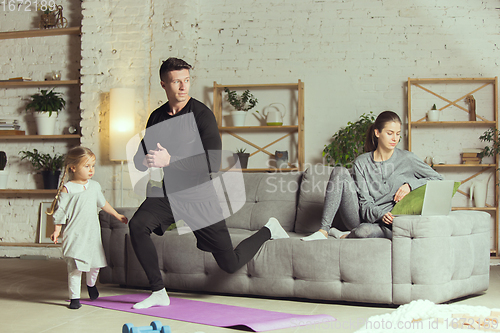 Image of Young man exercising fitness, aerobic, yoga at home, sporty lifestyle. Getting active during lockdown, quarantine. Home gym.