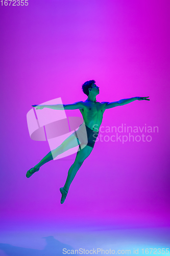 Image of Young and graceful ballet dancer isolated on purple studio background in neon light. Art, motion, action, flexibility, inspiration concept.