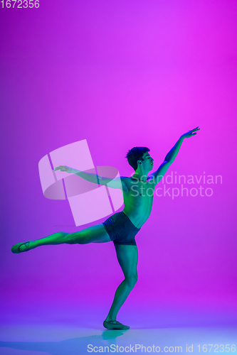 Image of Young and graceful ballet dancer isolated on purple studio background in neon light. Art, motion, action, flexibility, inspiration concept.