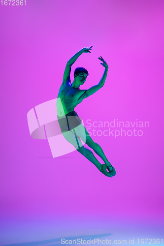 Image of Young and graceful ballet dancer isolated on purple studio background in neon light. Art, motion, action, flexibility, inspiration concept.