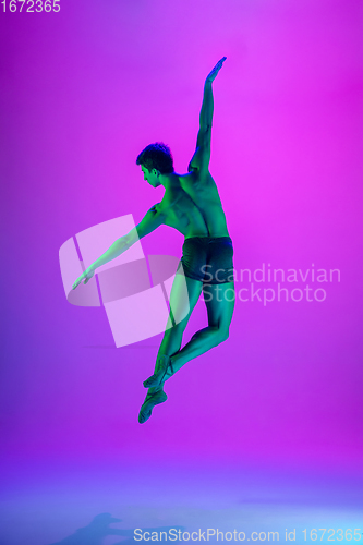 Image of Young and graceful ballet dancer isolated on purple studio background in neon light. Art, motion, action, flexibility, inspiration concept.