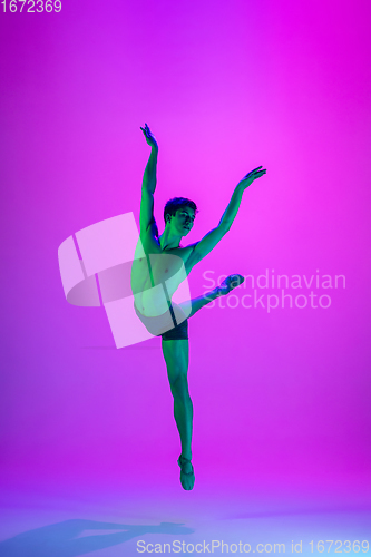 Image of Young and graceful ballet dancer isolated on purple studio background in neon light. Art, motion, action, flexibility, inspiration concept.